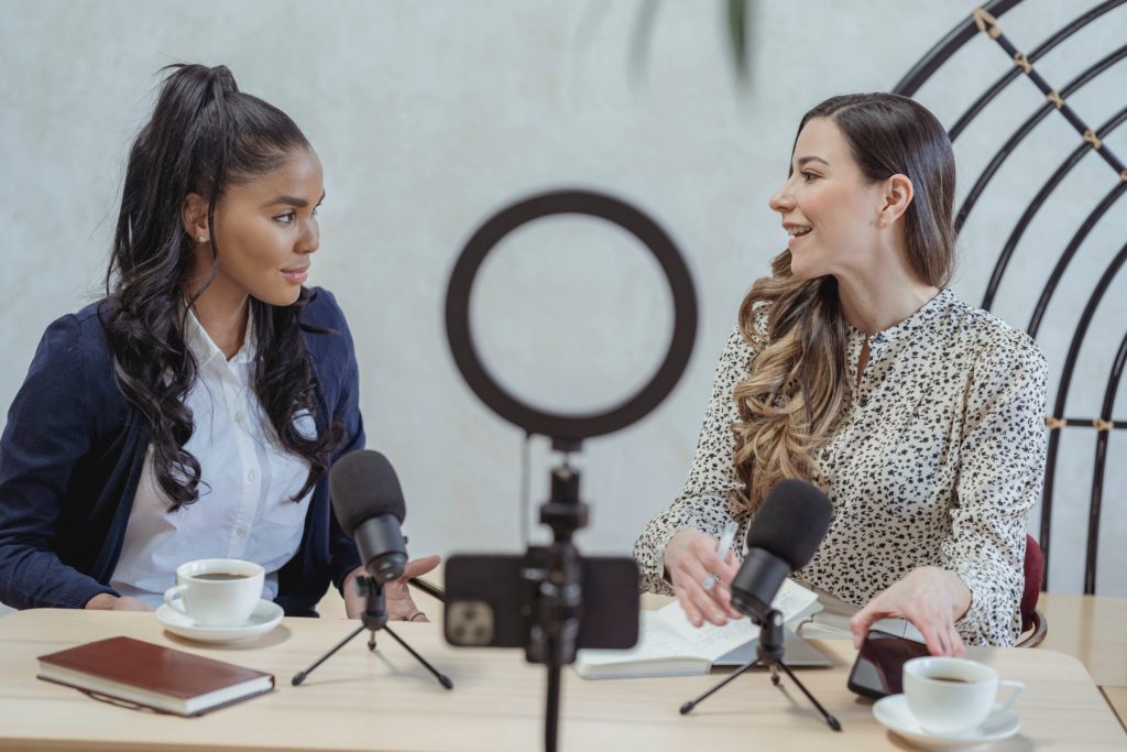 Two women talking while recording a podcast