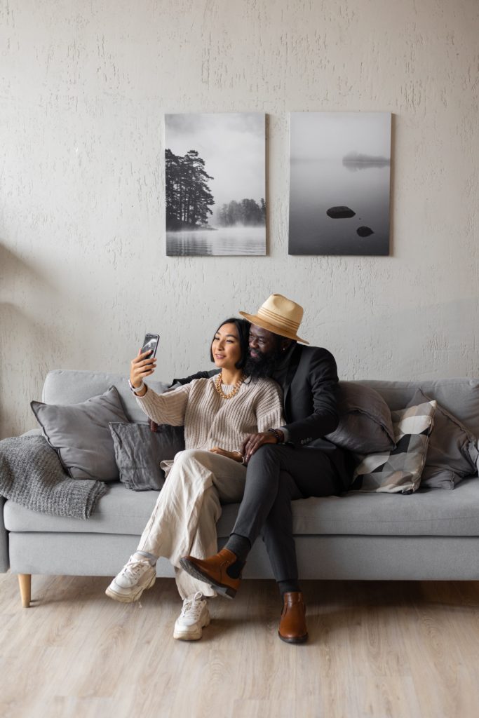 A couple sitting on a couch and taking a selfie together