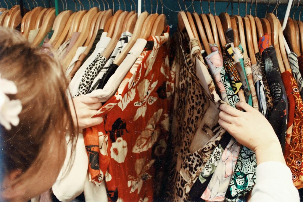 A girl going through a rack full of clothes. 