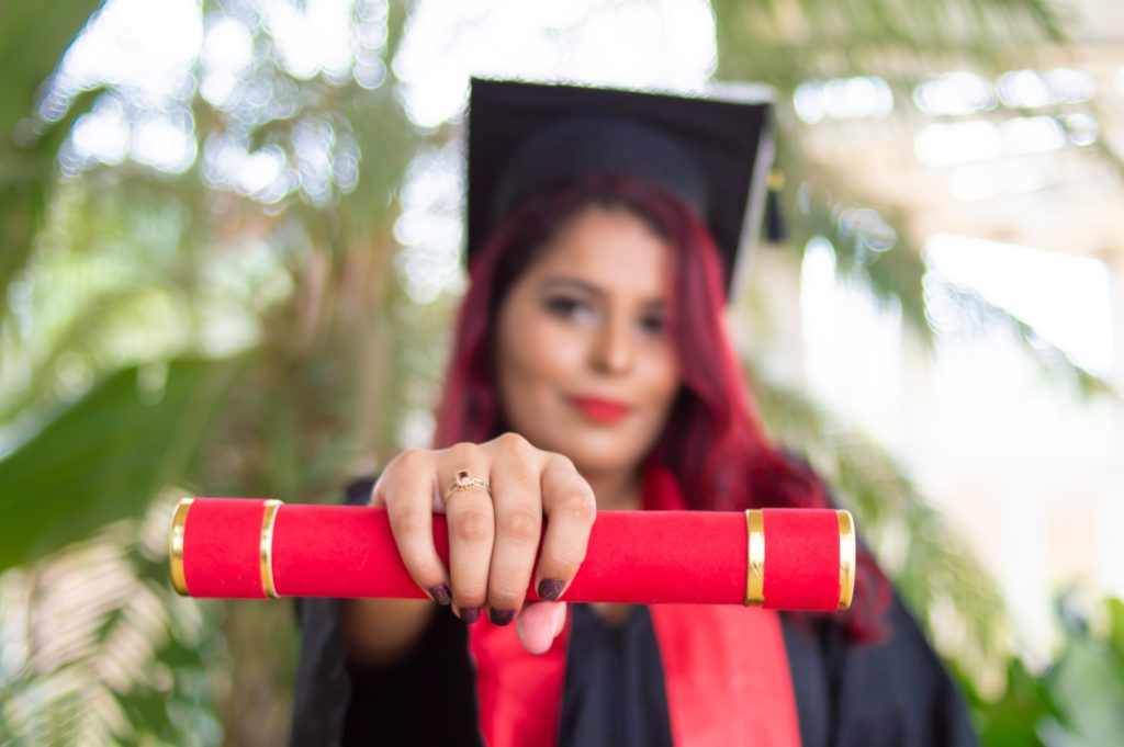 A young female graduate holding a college degree