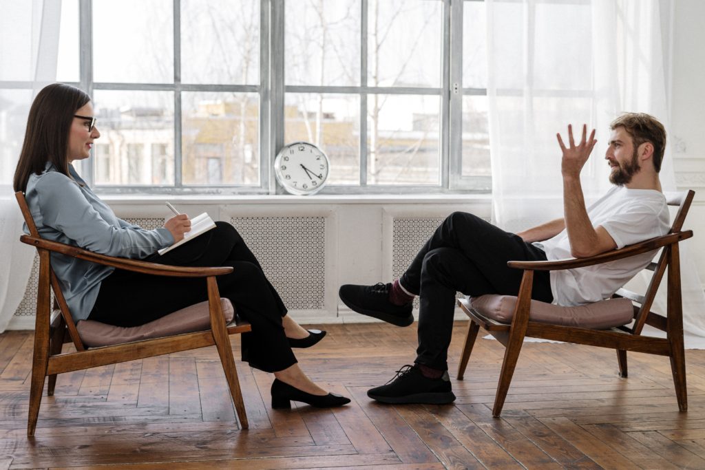 Two people in chairs consulting with each other.