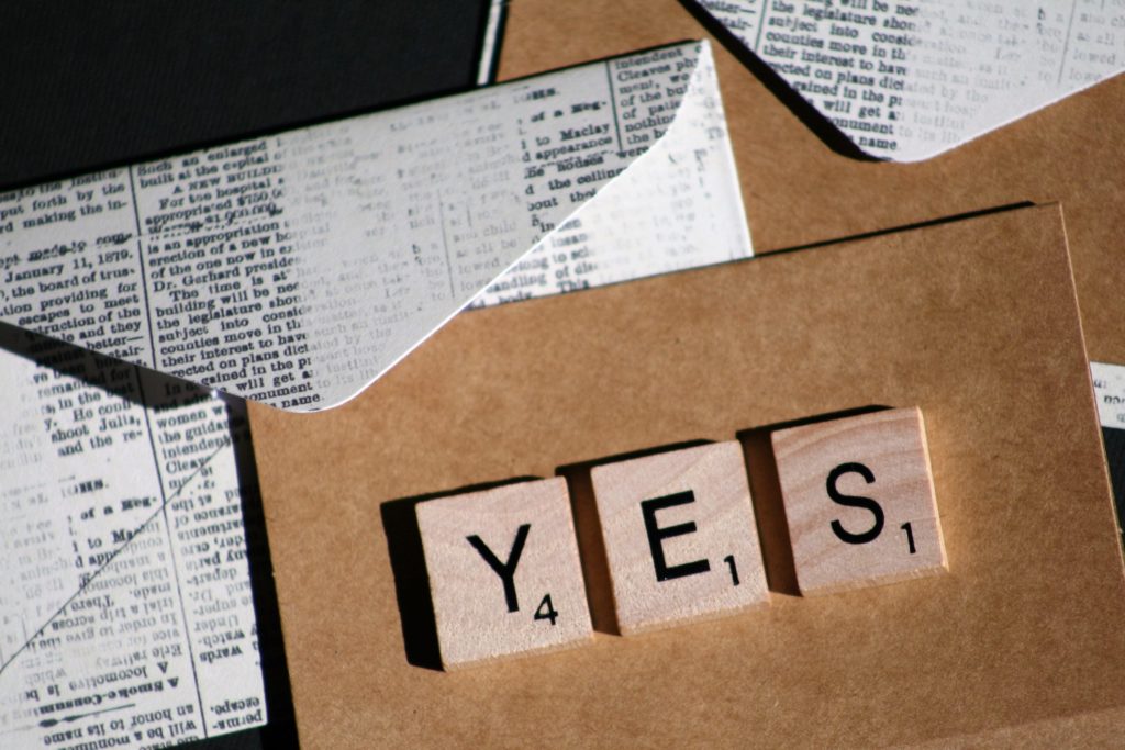 Printed envelopes with Scrabble tiles spelling the word "YES"