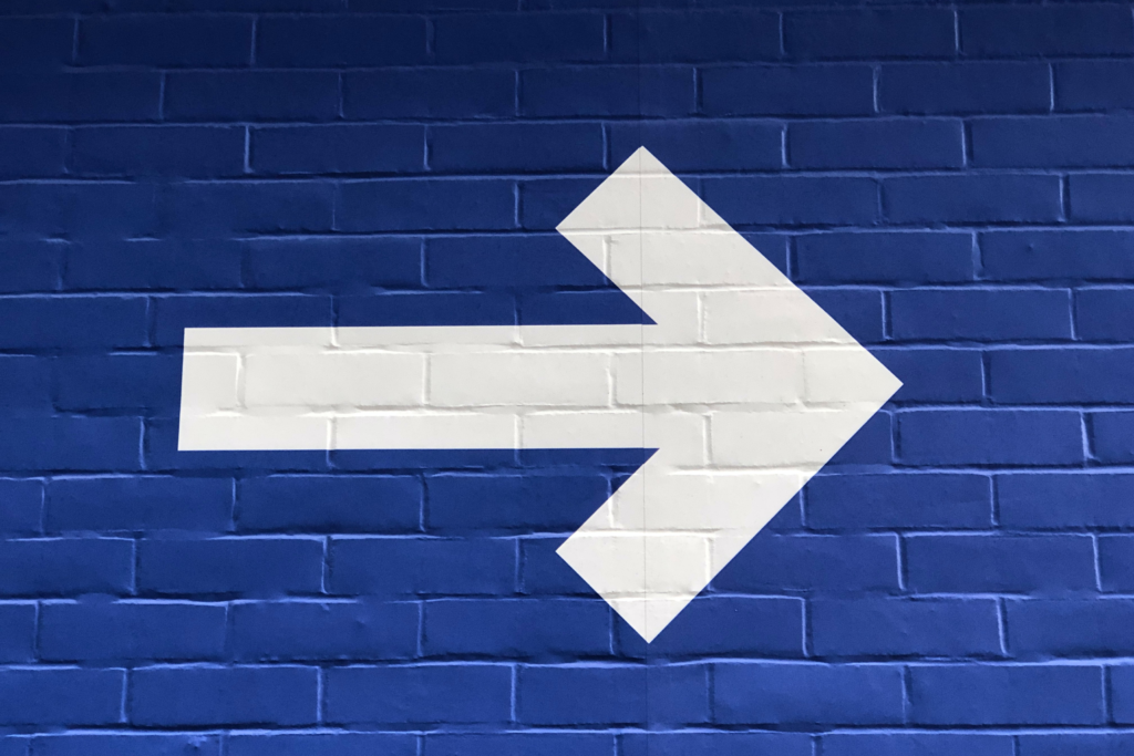 A mural of a white arrow on a blue wall