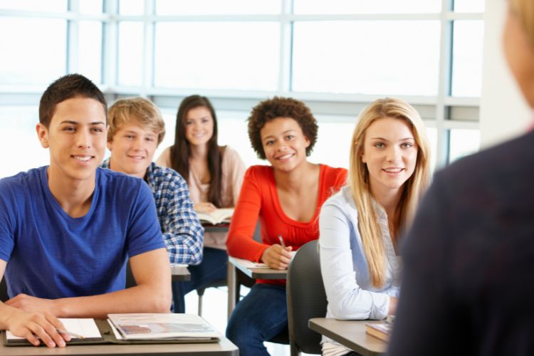 A group of students listening to a lecturer in a classroom.