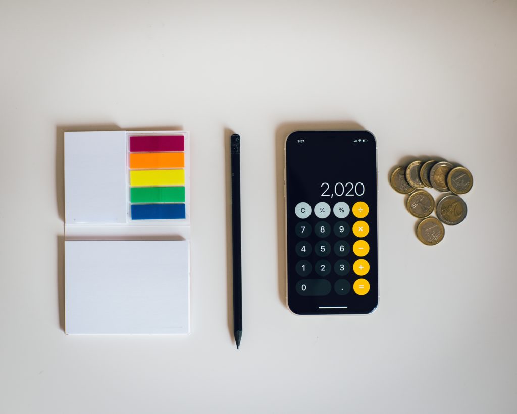 A calculator, coins, pen and a writing pad