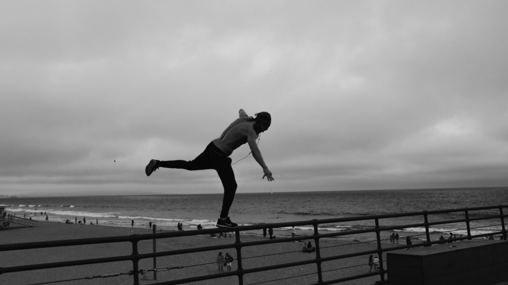 An athlete balancing on a rail fence at a beach