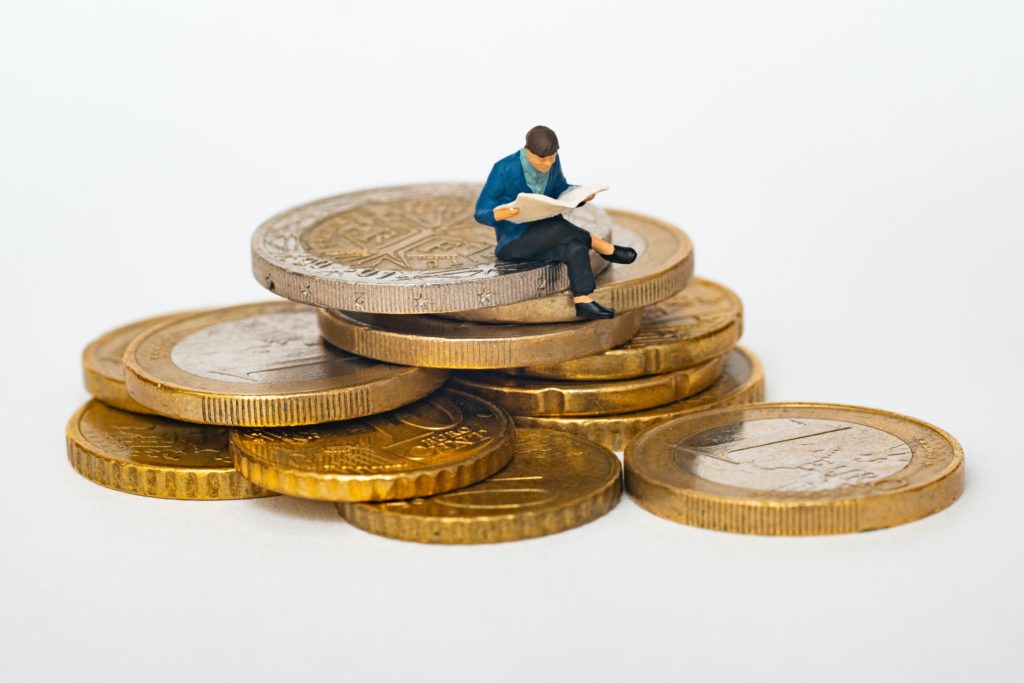 A stack of coins with a toy man sitting on top