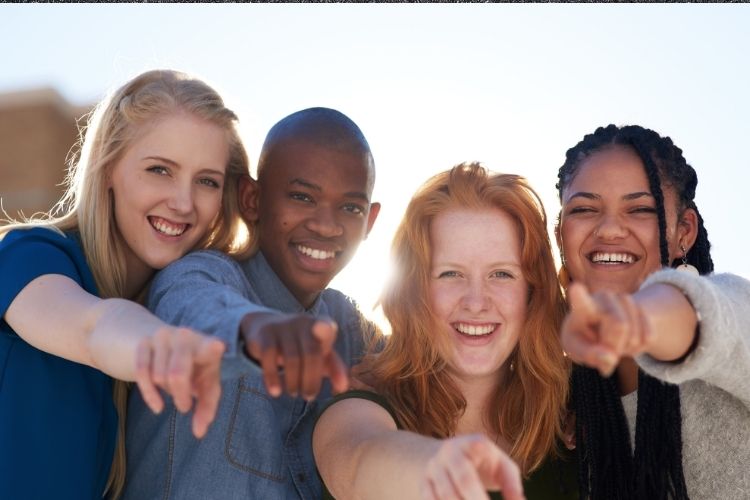 A picture of a group of young people all pointing at the camera.