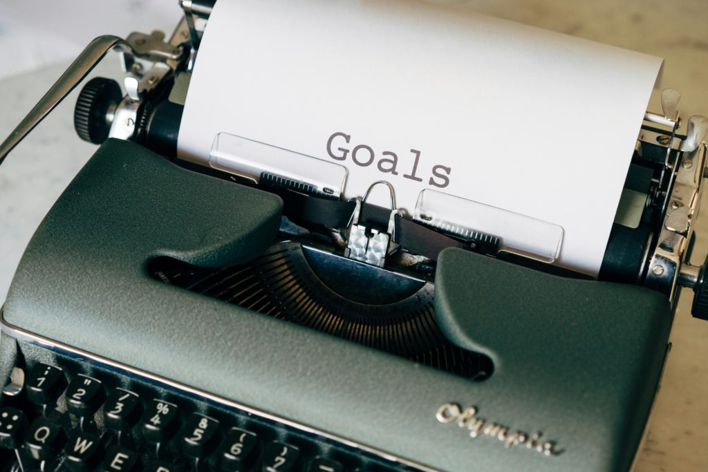 An old typewriter with a page with the words "Goals" typed on it.