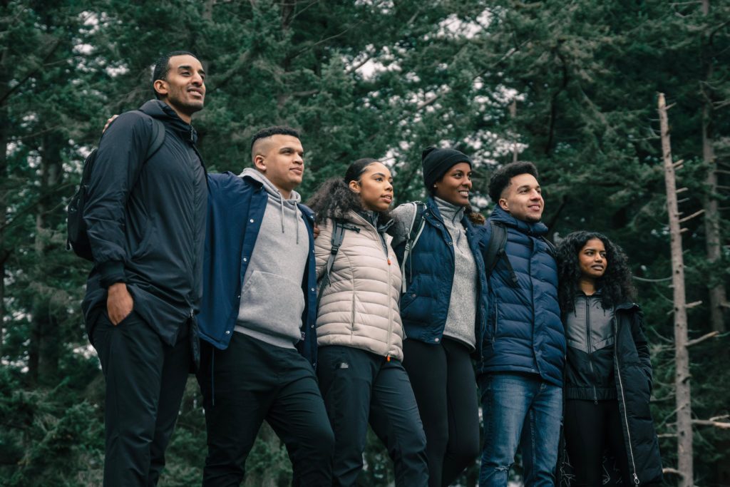 A group of young people in nature, standing side by side.