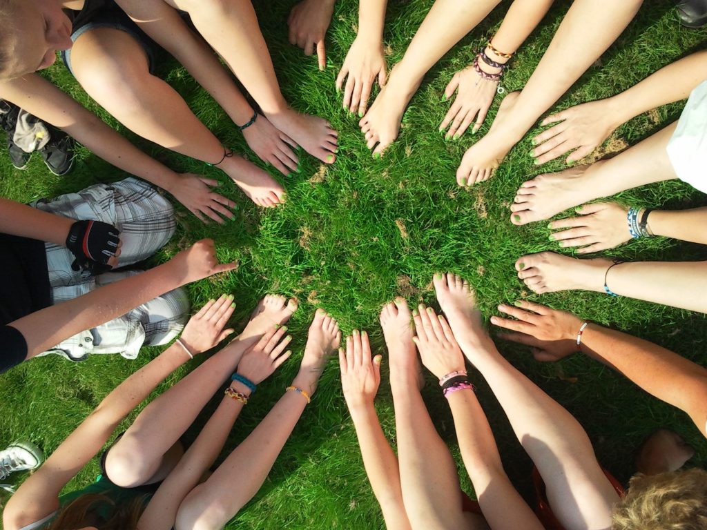A group of people sitting in a circle, putting their hands and feet in the circle.