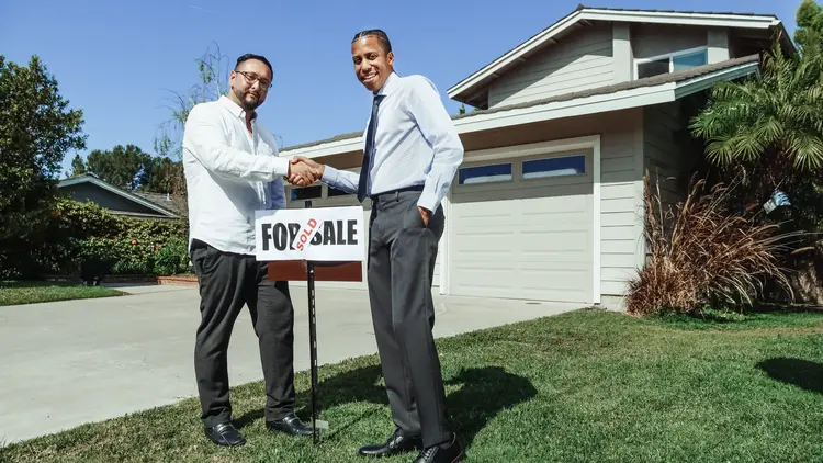 A real estate agent shaking the hand of a buyer. 