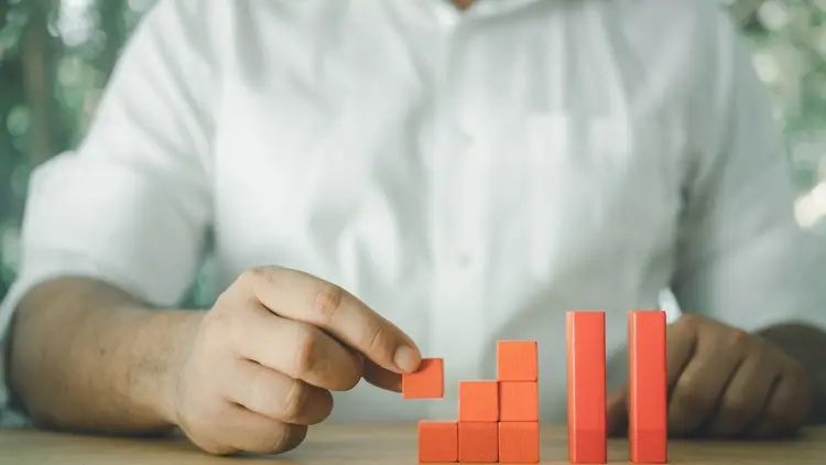A man using building blocks to create a tower, depicting growth.