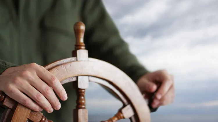 The Helm of a ship with someone steering it.