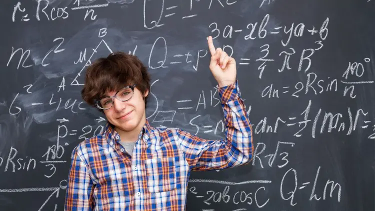 A student solving a chemistry problem on a chalkboard.