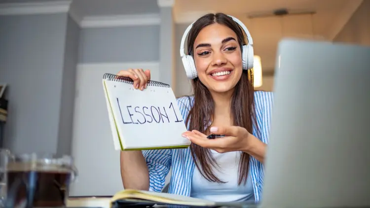 An online courseteacher holding up a sign saying "Lesson 1".