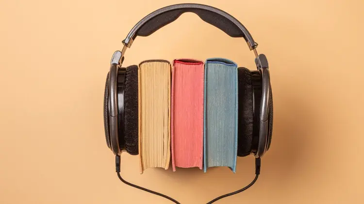 A set of 3 books with a pair of headphones over them, depicting audiobooks.