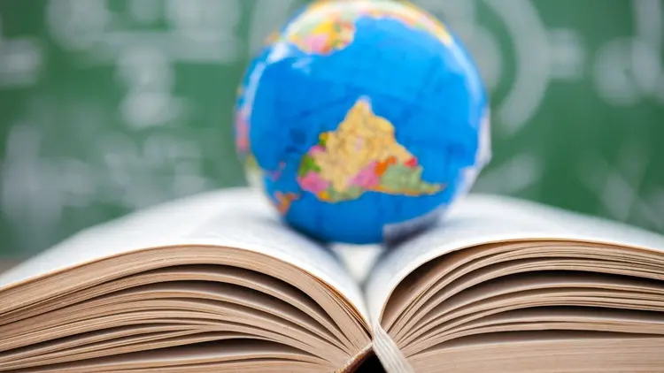 An open book with a globe depicting the world on it. 