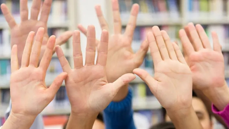 Raised hands in a classroom.