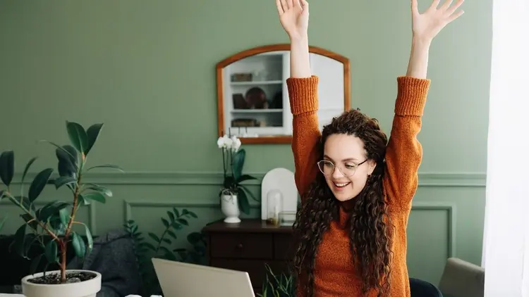 A woman raising her arms depicting success. 