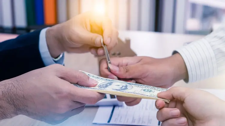 A close up of a person handing over cash and signing a document. 