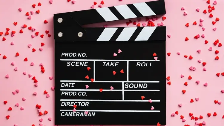 A movie clapper board set against a pink candy background.