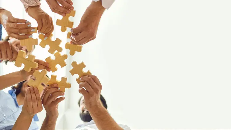 A group of people holding a puzzle piece in a circle. 