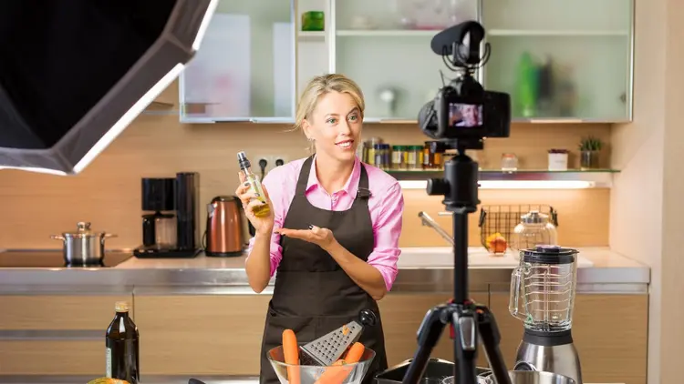 A lady in the kitchen recording a video. 
