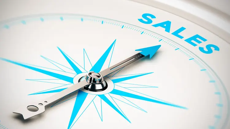 A compass with the needle pointing to the word "Sales"